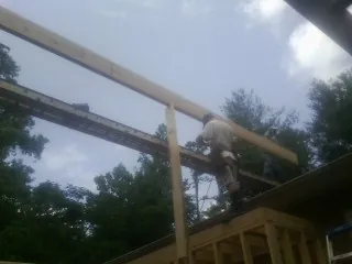 Carpenter setting a ridge beam over a new addition frame — Ice Dam Removal by Roofing Brothers in Winterville